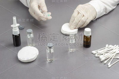 装有药物的玻璃瓶。手持医用手套，手持注射器。感冒药