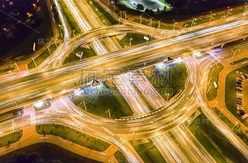 夜间城市道路十字路口的车灯痕迹。运动模糊。迂回的鸟瞰图。