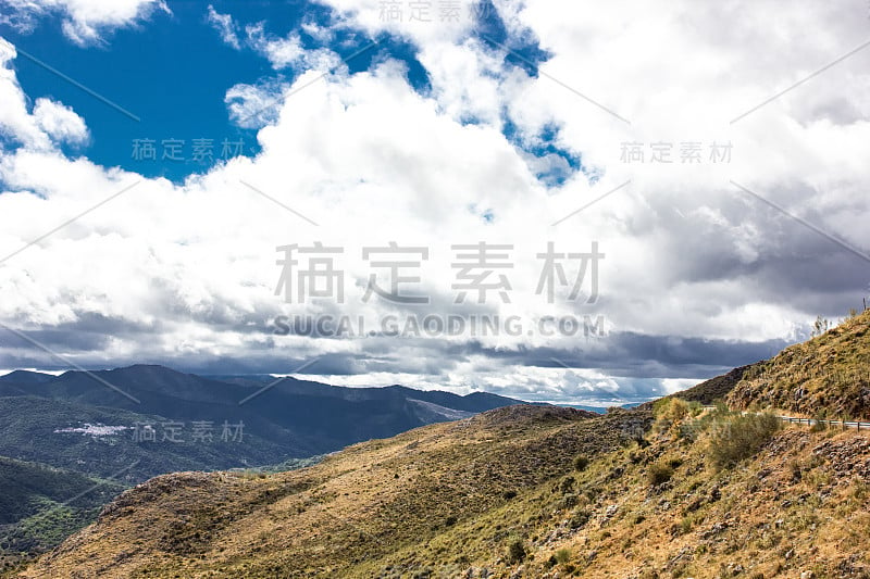 山景上的蓝色多云的天空背景。风景如画的群山在阳光下闪闪发光。令人屏息的自然影像