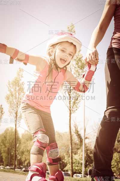 妈妈和小女孩在滑旱冰。在移动。