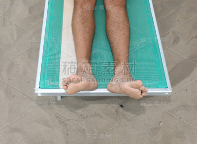 在海滩的躺椅上休息的人的脚