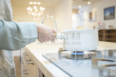 在煤气炉上做饭的年轻女人的手