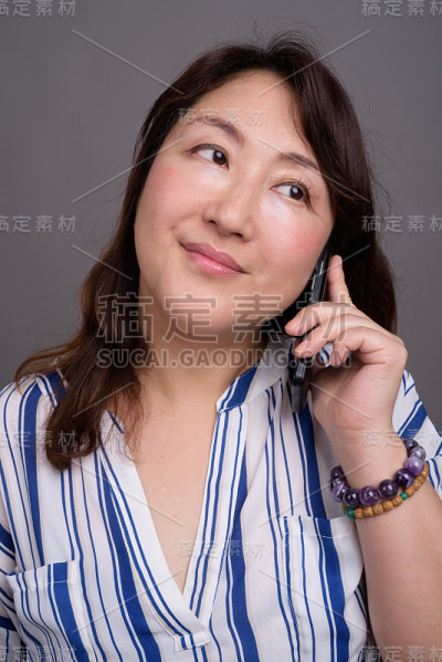 工作室拍摄的成熟美丽的亚洲女商人在灰色的背景