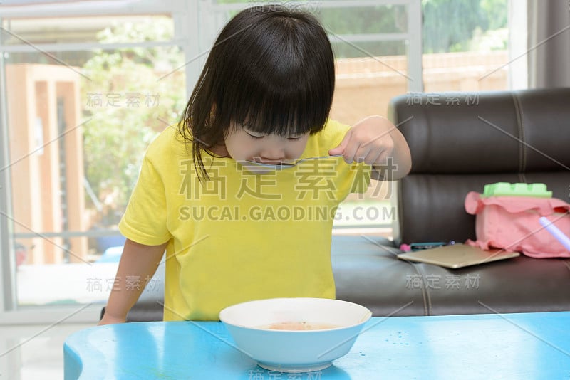 这个亚洲小女孩早餐喜欢用勺子喝汤。