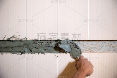 工人正在往墙上抹水泥。砂浆抹灰过程。图片的文章