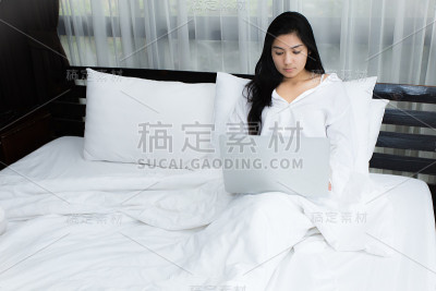 一个女人在床上用笔记本电脑