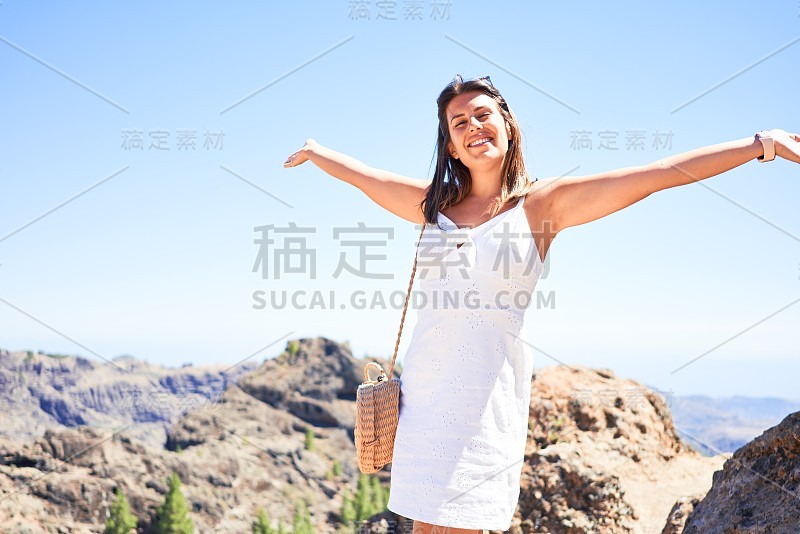 年轻美丽的女人享受暑假在山的景观，快乐地微笑在罗克努布洛山顶在大加那利亚