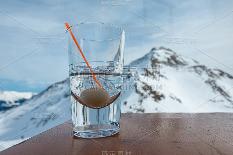 桌子上放着一杯酒，背景是白雪覆盖的山脉