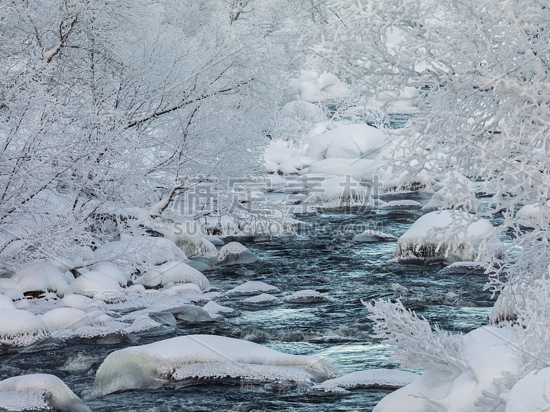 一条冬季流淌的小溪，冰雪覆盖，河流周围的树木被雪覆盖