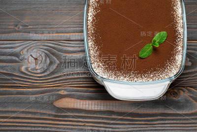 传统的意大利提拉米苏甜点在玻璃烤盘木制背景