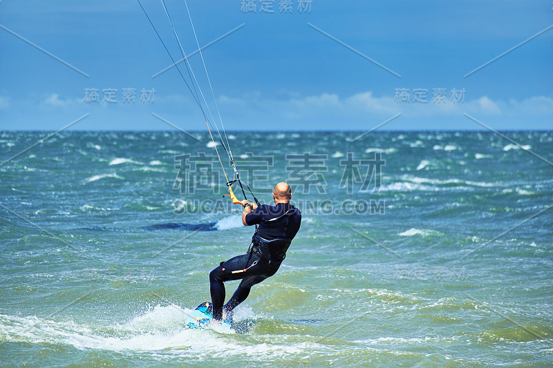 在夏天，人们骑着风筝在海浪上冲浪。