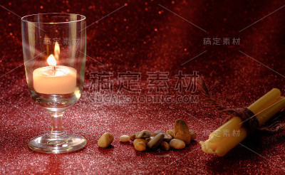 金色的烛光在酒杯中燃烧，带有灯光效果和红色模糊的散景背景