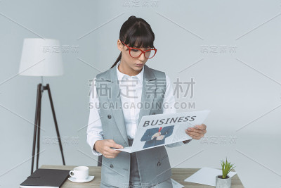 女商人孤立地看灰色的报纸