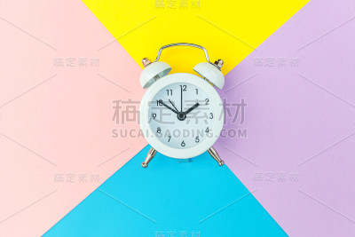 响双铃经典闹钟孤立在蓝黄粉彩色几何背景。休息小时，生活时间，早安，晚安，醒来，清醒的概念。平放俯视图