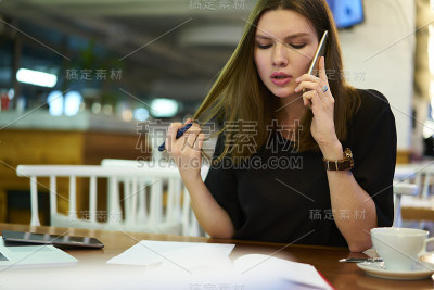 自助餐厅的年轻女经理查看银行账户，在手机上阅读文件信息，忙碌的员工通过电话预订，坐在咖啡厅查看预订