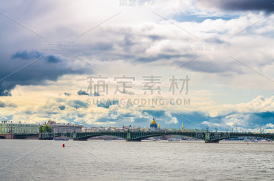 圣彼得堡(列宁格勒)城市景观与三一桥(巴克尔桥)横跨涅瓦河和圣以撒大教堂的金色圆顶背景，蓝色多云戏剧