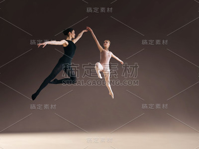 两个芭蕾舞者在空中跳得很高。