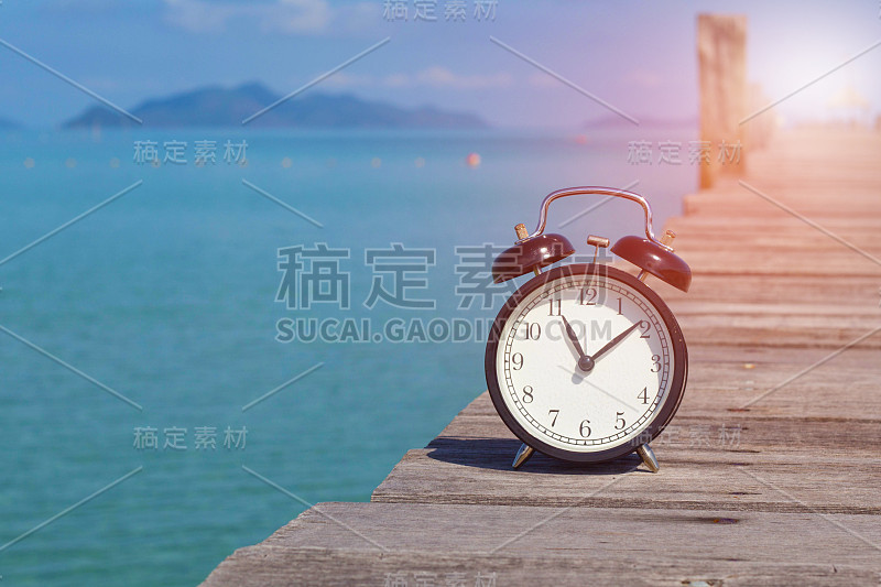 11点u2019时钟的复古闹钟放在以大海为背景的木桥上。