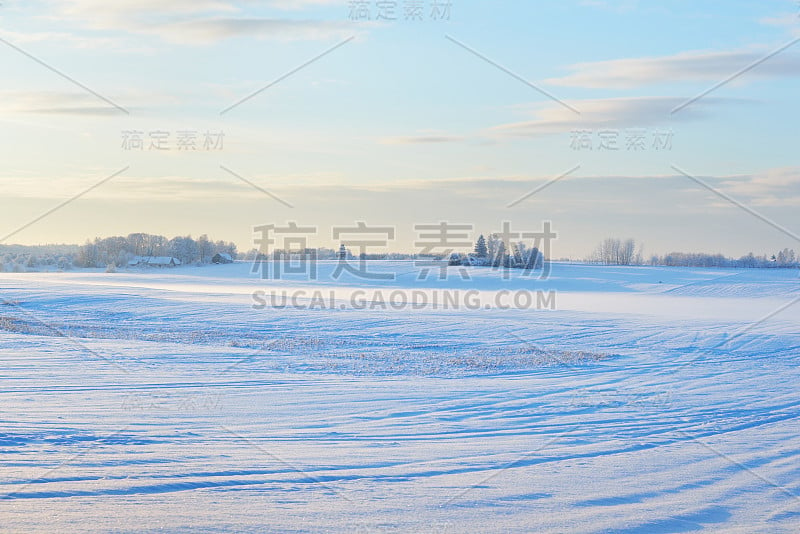 冬天的风景。日落时分白雪覆盖的农田。