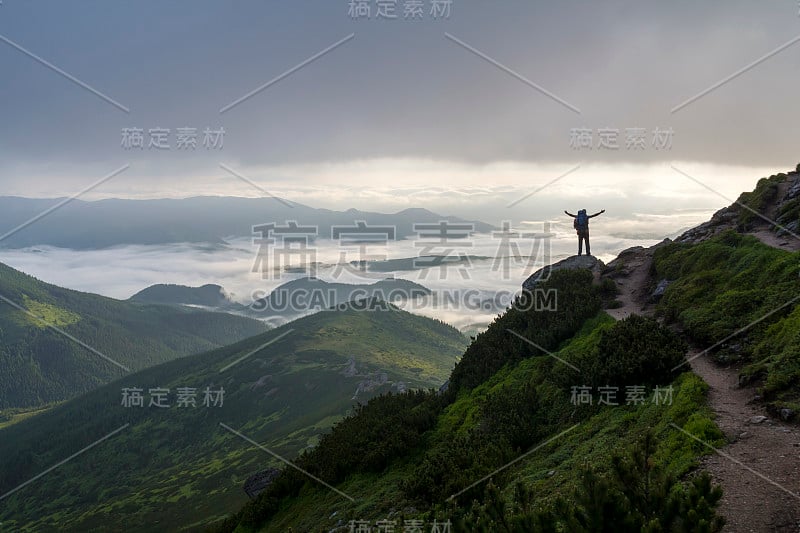 宽山全景。小剪影的游客背包在岩石坡与高举的手山谷覆盖着白色的蓬松的云。自然之美，旅游与旅游理念