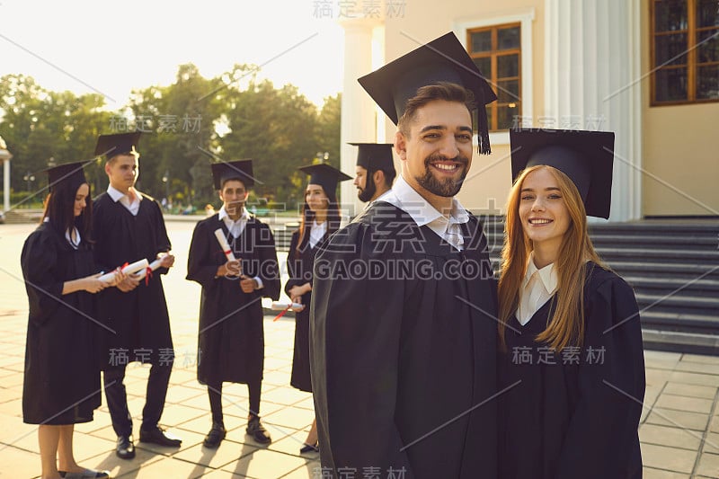 年轻微笑的一对男女学生大学毕业生站在镜头前