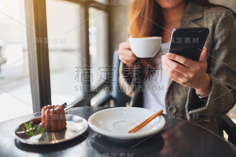 一个女人拿着手机在咖啡厅喝咖啡