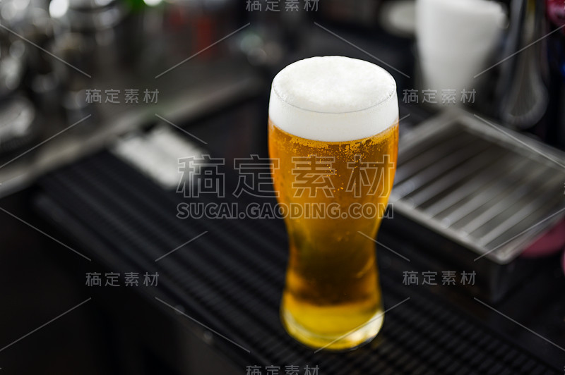 一杯啤酒在餐厅的空中吧台上投下了阴影。冰啤酒，下班后出去玩再好不过了。啤酒，闲逛，放松，餐厅，晚餐的