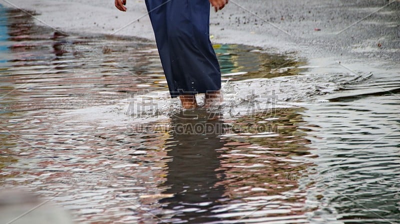 在仍然下雨的情况下步行穿过被洪水淹没的道路