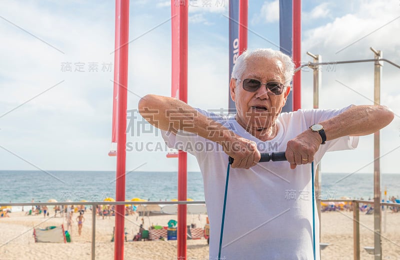 一名老人(80-89岁)在巴西里约热内卢伊帕内玛海滩的露天健身房用一根弹力绳锻炼