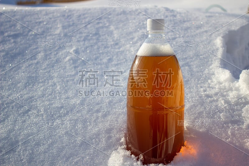 塑料啤酒瓶在冬天的大自然中，以啤酒为背景。