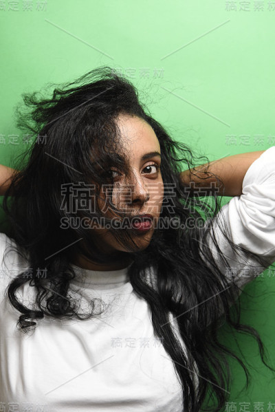 有着一头黑发的中东年轻女子。室内照片的奇妙女性模特在绿色的背景。