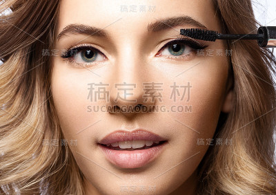 女人在用黑色的睫毛膏化妆