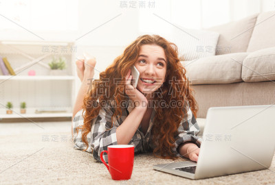 地板上躺着手提电脑和手机的女孩
