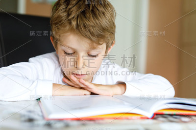 金发小男孩在家里看书