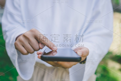 女性手用智能手机在公共自然空间里办公、社交、交流。