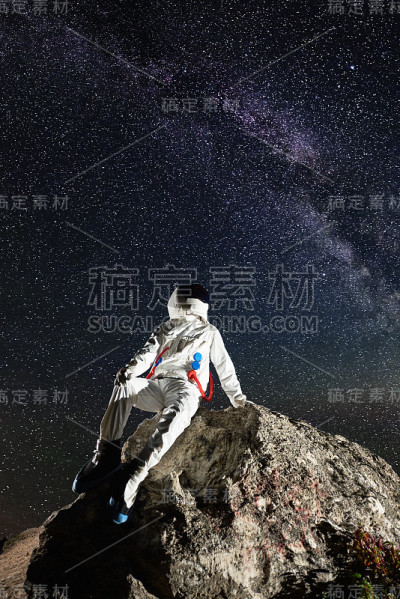 宇航员坐在岩石山上看星星。