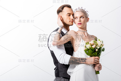 美丽的纹身新娘和英俊的新郎拥抱孤立在白色