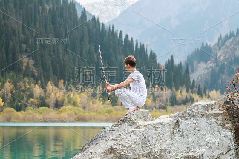 一个聪明人坐在石头上，手里拿着一把剑。山湖背景