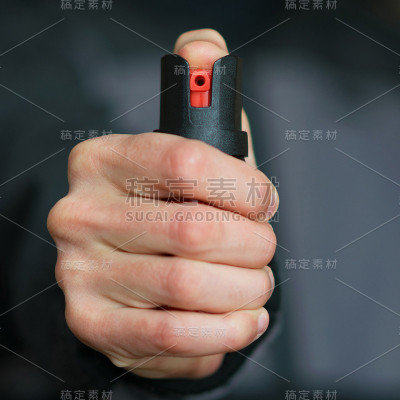 手持胡椒喷雾(催泪瓦斯)的男子。自卫。模糊背景，方形，特写