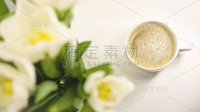 清晨一杯咖啡，旁边是一束白色郁金香。春天的节日卡片。