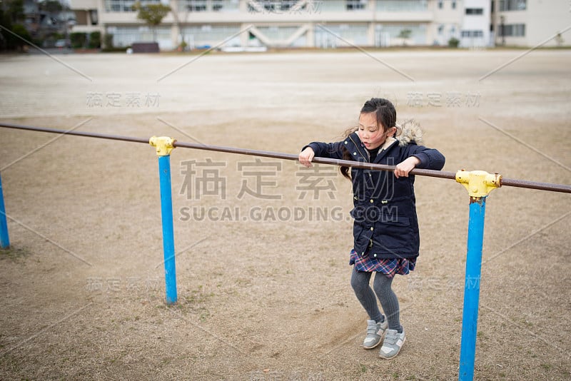 在操场上玩单杠的女孩