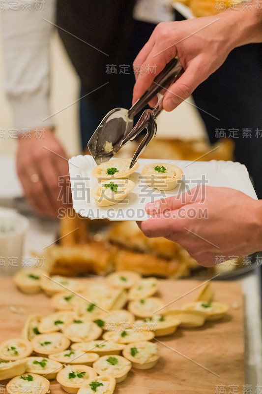 近距离拍摄在自助餐厅的自助餐桌上，男人用餐具夹取食物。