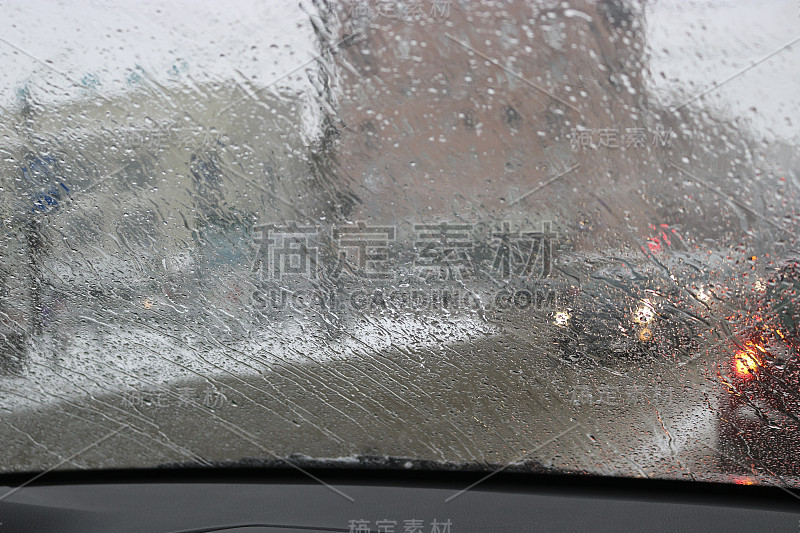 雨和湿雪期间从汽车挡风玻璃观看。在市内开车时能见度低。雪道路。