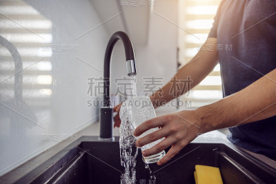 特写的男子装满了新鲜的水从水龙头的玻璃。