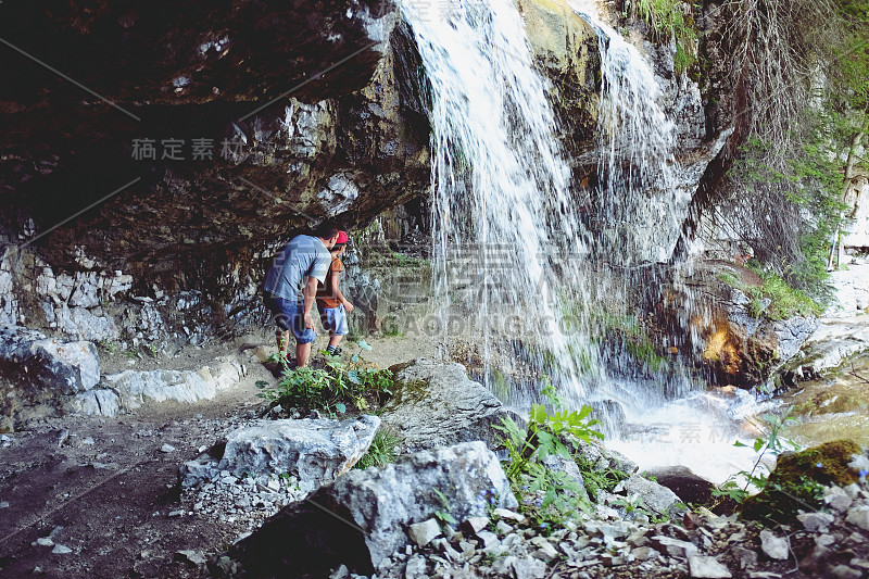 一名白人男子和他的儿子在奥地利阿尔卑斯山脉的瀑布下漫步