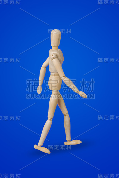 行走的木制玩具人物在蓝色