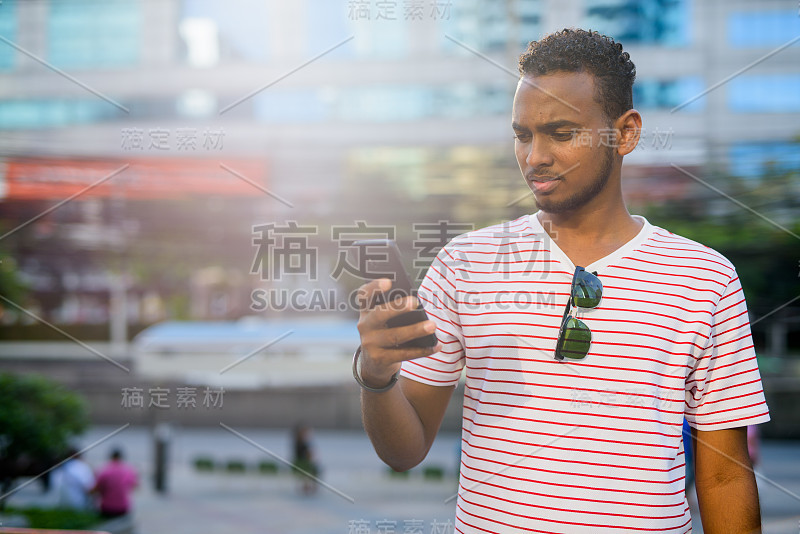 年轻英俊的蓄着胡子的非洲男人在城市里打电话