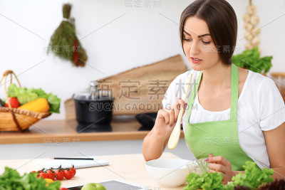 美丽的西班牙女人在厨房做饭