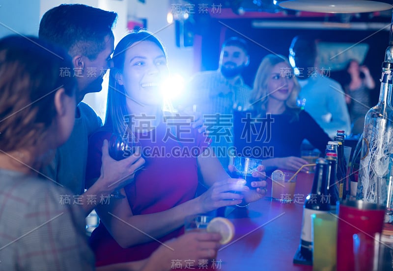 快乐愉快，积极微笑的女人和男人在夜店里喝酒作乐