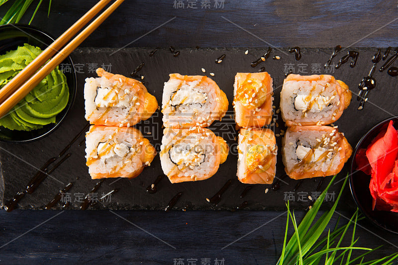 一套烤寿司卷与芥末和生姜在黑色的背景。日本东方美食